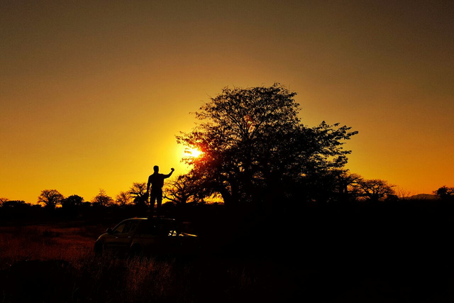 Sunset Silhouette photo of a man standing on top of an off-road vehicle, photographing a Baobab tree in Mozambique. NightOwl Media, Corporate Photography. Photographer based in Pretoria & Johannesburg, Gauteng, South Africa. Videographer, Marketing