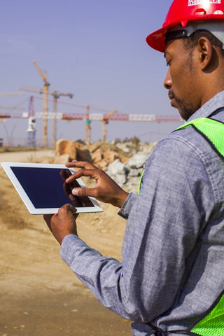 Photo of an engineer on a construction site, inspecting and documenting on a tablet. NightOwl Media, Corporate Photography. Photographer based in Pretoria & Johannesburg, Gauteng, South Africa. Videographer, Marketing, Incentive, industrial, mining